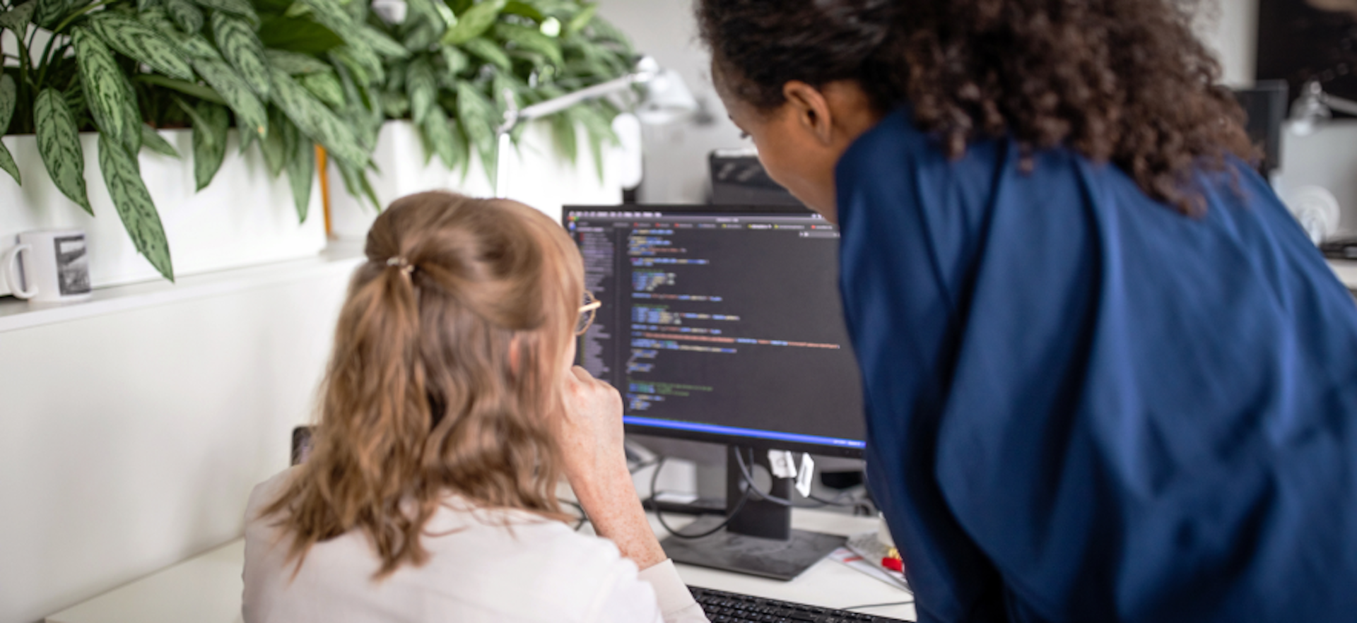 Mujeres mirando código en un monitor